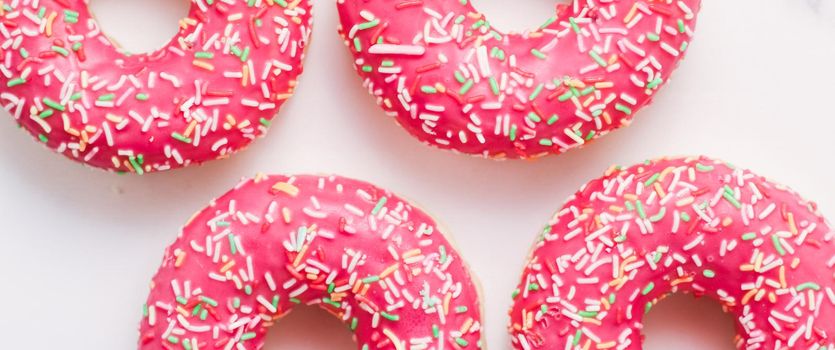 Bakery, branding and cafe concept - Frosted sprinkled donuts, sweet pastry dessert on marble table background, doughnuts as tasty snack, top view food brand flat lay for blog, menu or cookbook design