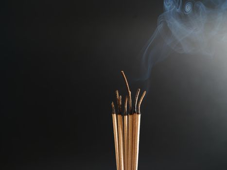 Burning incense white smoke black background used as a worship background image a sacred object of Buddhist beliefs focus on the smoke