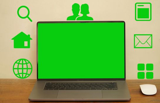 An abstract green screen laptop and mouse placed on a long desk with icons showing symbols to take advantage of the various programs.