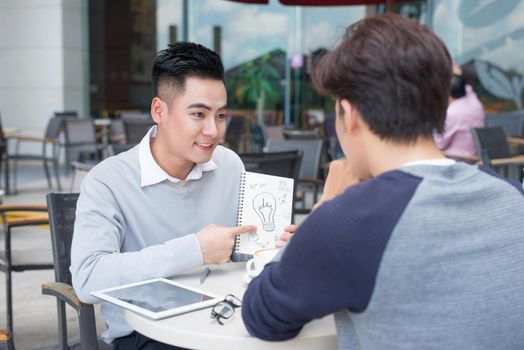 Two cheerful asian business people discussing with documents