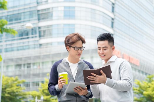 Coffee break. Two cheerful business men talking while one of them holding coffee cup