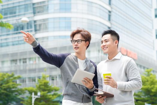 Coffee break. Two cheerful business men talking while one of them holding coffee cup