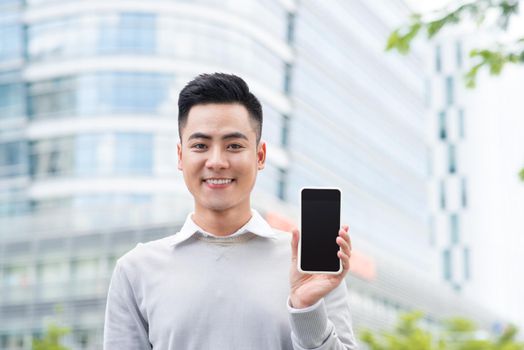 Businessman holding and showing screen of cellphone