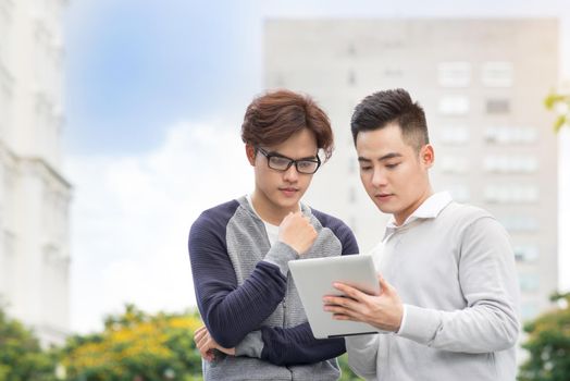 Asian business people discussing information on tablet computer