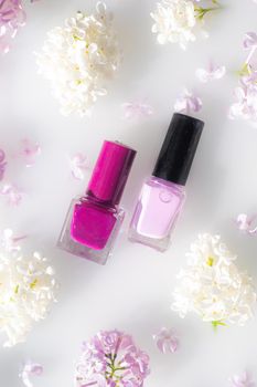 Lilac nail polish and a branch of lilac . A bottle of nail polish without a name. The concept of advertising the products of lacquers . Beauty and fashion. Nail care. Spring