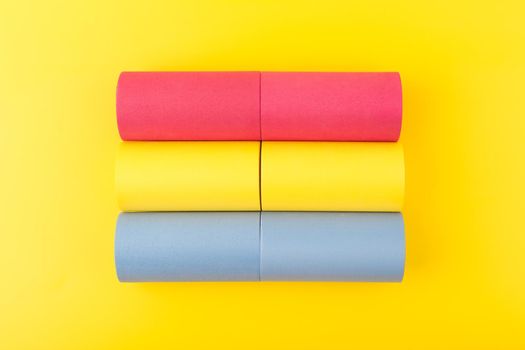 Flat lay with pansexual flag made of pink, yellow and blue rolls on yellow background. Concept of pansexual community, respect and equal rights for sexual minorities