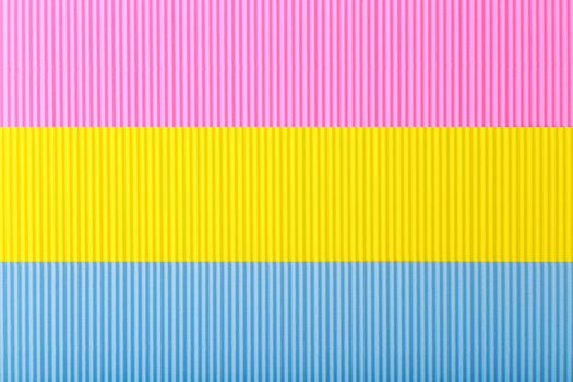 Top view of pansexual textured flag made of pink, yellow and blue pieces of corrugated paper. Concept of pansexual pride background and lgbtq plus community