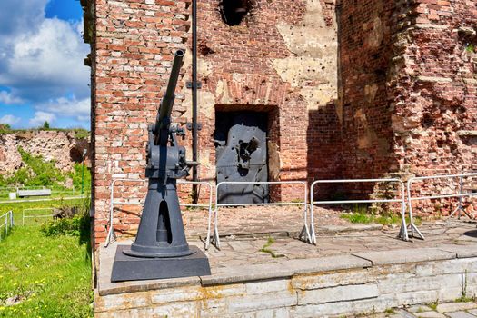 Antiaircraft gun of the second world war next to the ruins of red brick. Oreshek fortress