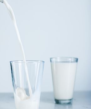 Dairy, healthy nutrition and breakfast concept - World Milk Day, pouring into glass on marble table