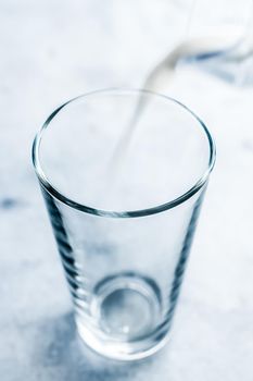 Dairy, healthy nutrition and breakfast concept - World Milk Day, pouring into glass on marble table