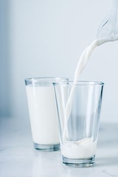 Dairy, healthy nutrition and breakfast concept - World Milk Day, pouring into glass on marble table