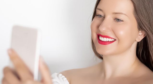 Happy smiling woman with smartphone having video call or taking selfie, portrait on white background. People, technology and communication concept.