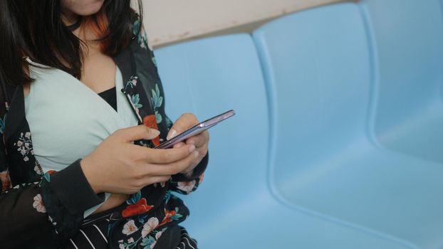 Young woman standing on the subway train in the morning during going to work and using smartphone for chat social media, people transportation concept 