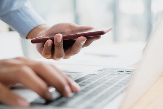 Close-up view of young professional businessman using smartphone connect with computer laptop