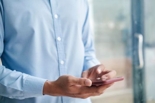 Close up shot of man's hands holding mobile phone while using wireless high-speed Internet connection.