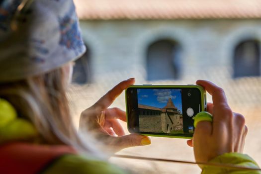 girl photographs the landmark on a mobile phone. Taking a photo on a smartphone while traveling. Fortress Oreshek