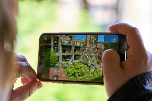 Hand holds mobile phone taking pictures of the old fortress. Taking a photo on smartphone while traveling. Fortress Oreshek
