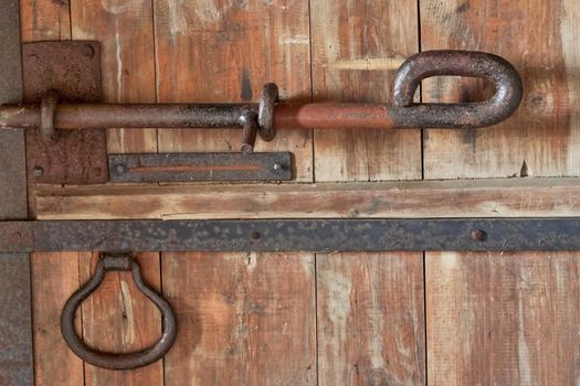 Fragment of an old fortress door with forged metal bolts and locks. Antique locks on wooden gates