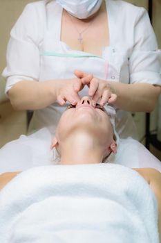 The girl is given a face and neck massage in a beauty salon. Enjoy the procedure