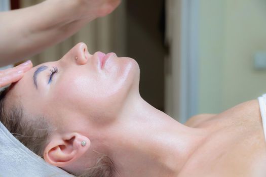 The girl is given a face and neck massage in a beauty salon. Enjoy the procedure