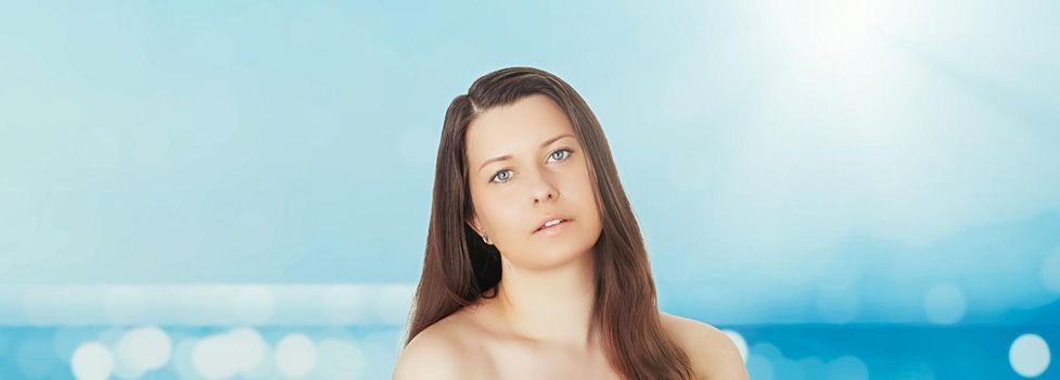 Skincare and sun protection in summer. Portrait of a beautiful young suntanned woman, blue sea and sky on background, beauty, wellness and travel concept.