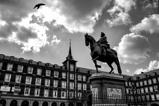 Beautiful equestrian statue of Felipe III in the main square in Madrid called Plaza Mayor with its majestic facades in a sunny day of Spring