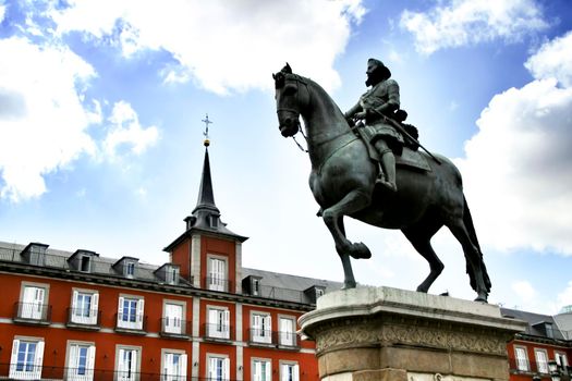 Beautiful equestrian statue of Felipe III in the main square in Madrid called Plaza Mayor with its majestic facades in a sunny day of Spring