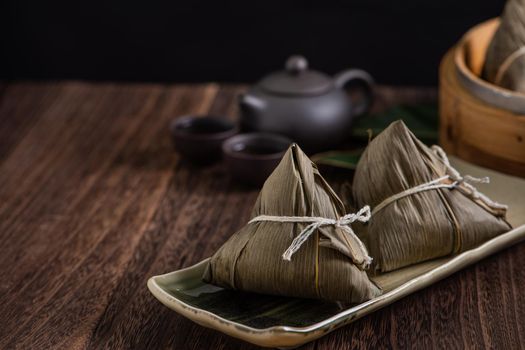 Zongzi. Rice dumpling for Chinese traditional Dragon Boat Festival (Duanwu Festival) on dark wooden table background.