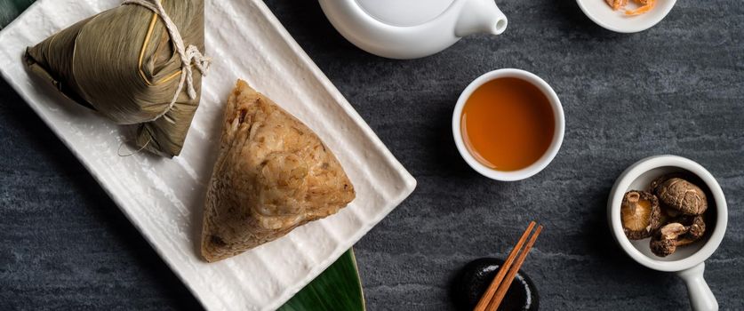 Zongzi. Rice dumpling top view design concept for Chinese traditional Dragon Boat Festival (Duanwu Festival) over dark black slate background.