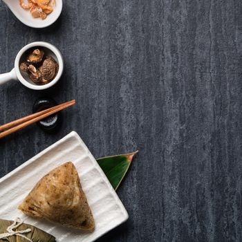 Zongzi. Rice dumpling top view design concept for Chinese traditional Dragon Boat Festival (Duanwu Festival) over dark black slate background.