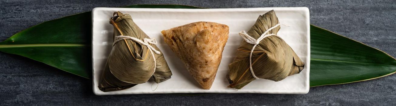 Zongzi. Rice dumpling top view design concept for Chinese traditional Dragon Boat Festival (Duanwu Festival) over dark black slate background.
