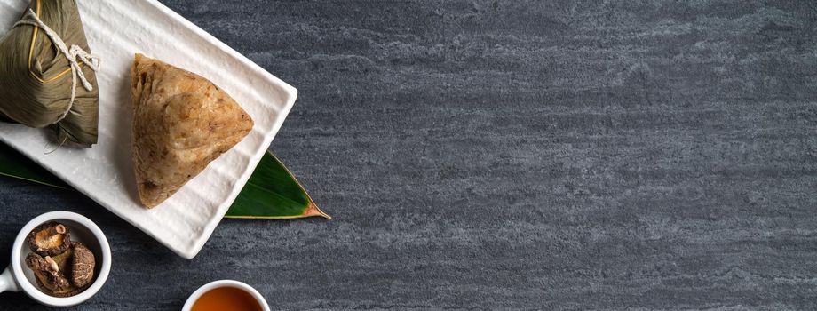 Zongzi. Rice dumpling top view design concept for Chinese traditional Dragon Boat Festival (Duanwu Festival) over dark black slate background.