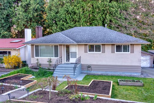 A perfect neighborhood. Residential family house with gardent patches in wooden beds on the front yard