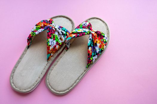 Colored home women's slippers on a pastel paper pink background. Top view. Copy space.
