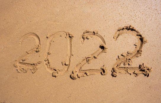The numbers 2022 on the wet sand. The concept of the New Year 2022. Summer holidays and sea trips.