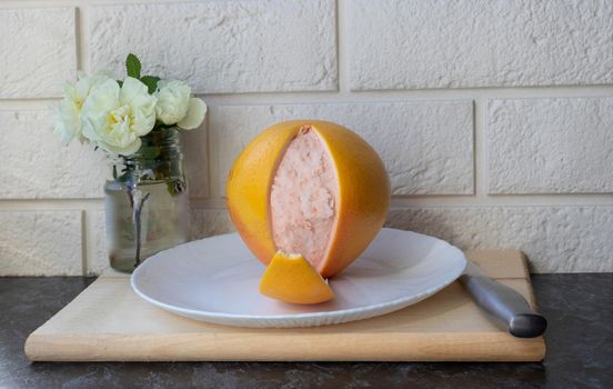 Fresh healthy grapefruit on a white plate on the kitchen table. Creative concept of minimal food. Grapefruit slices of citrus.