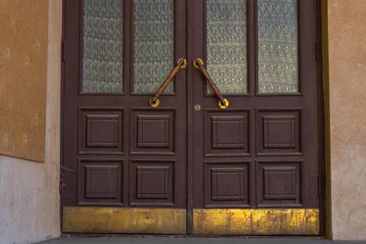 Antique door handles on a brown wooden door with fluted panes.