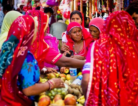 Pushkar, India - November 10, 2016: Few Indian women in colorful saree while covering their head buying fruits in group in the state of Rajasthan