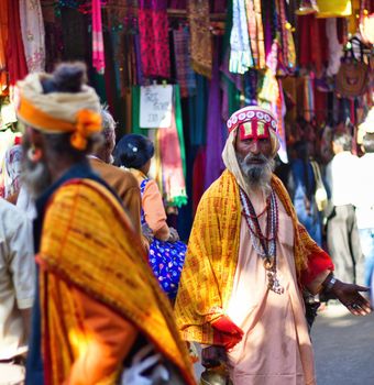 Pushkar, India - November 10, 2016: A bearded hindu old man with vishnu tilak on his forehead and orange ethnic wear walking in famous pushkar mela or fair in the state of Rajasthan
