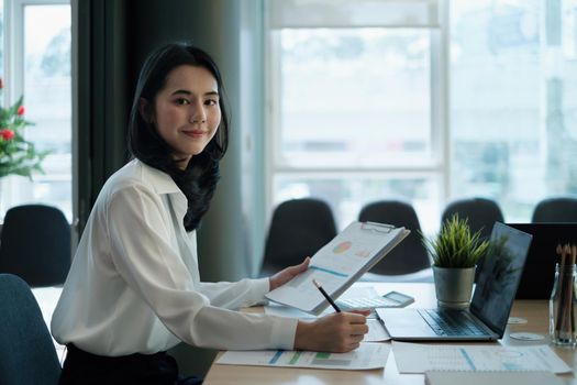 Portrait of a smiling entrepreneur or accountant while working with paperwork in office at her corporate