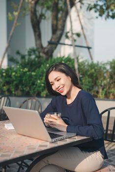 Taking advantages of free Wi-Fi. Beautiful young woman working on laptop and smiling while sitting outdoors