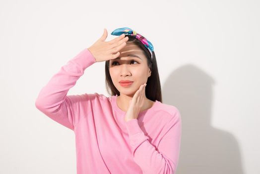 Portrait of a beautiful Asian girl  covering face by hand of bright sun light. Woman in a pink dress protecting her face from solar light. Skin care or beauty concept