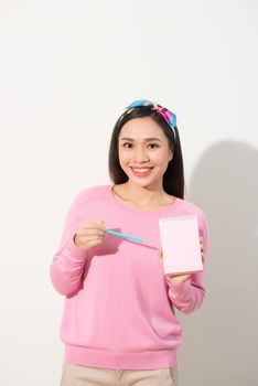 Closeup image of a beautiful Asian woman holding and showing blank notebook 