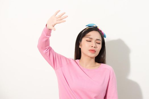 Portrait of a beautiful Asian girl covering face by hand of bright sun light. woman in a pink dress protecting her face from solar light. Skin care or beauty concept