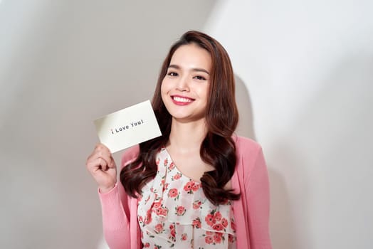 beautiful young woman with a Valentine's card in her hands, isolated against white background