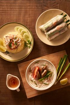 Assorted asian dinner, vietnamese food. Chicken rice, bun cha ca, noodles, spring rolls