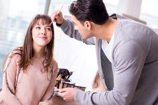 Man doing make-up for cute woman in beauty salon