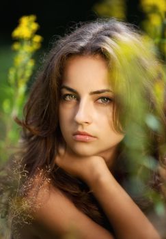 Soft portrait of a young woman on flowers field blured background