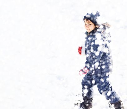 Cute boy playing with snow in the winter park  during a snowfall on a winter day