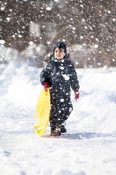 Boy with sleigh. Sledding during a snowfall on a winter day